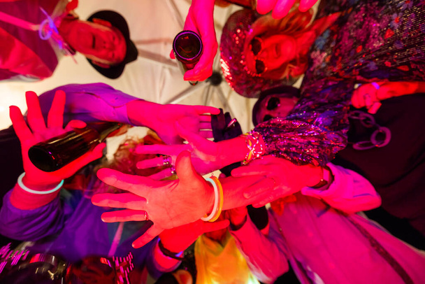 Ez az élénk kép megragadja az ünneplés pillanatát, felülről nézve, ahogy egy baráti társaság összejön egy dinamikus tósztban. A kezük, a koccintó üveg és a szemüveg, a fókuszpont, készlet - Fotó, kép