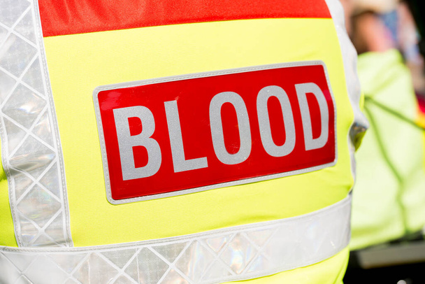 Слово "BLOOD" на червоному тлі, прикріпленому до задньої частини відбиваючої куртки. - Фото, зображення