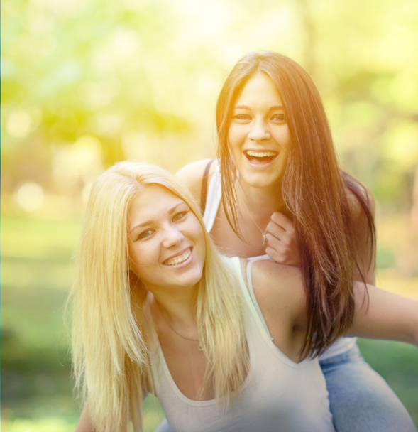 Primer plano retrato de dos chicas felices abrazándose al aire libre
 - Foto, Imagen
