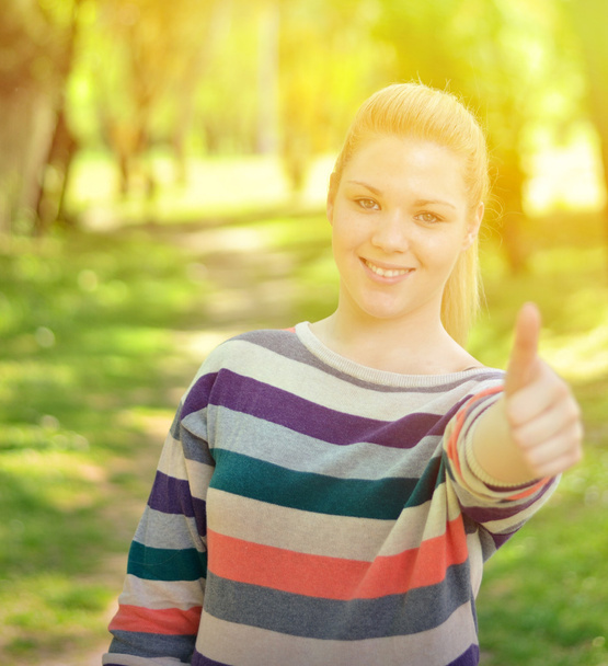 Portrait of beautiful girl holding thumbs up outdoors - Foto, Imagem