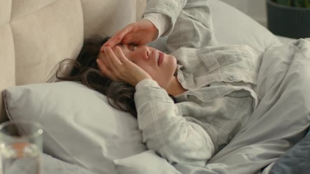 Kavkazská bruneta nešťastná žena probudit se na posteli ložnice doma uvnitř drží hlavu migréna bolest hlavy masáže spánky nezdravé nepohodlí nemoc dívka bolestivé utrpení dotýká unavené ženské nemoci - Záběry, video