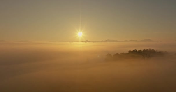 Légi kilátás A reggeli nap arany fénye a köd tengere felett. A völgyben nyugodt esti hangulatot teremt. Színes színek a hegység - Felvétel, videó