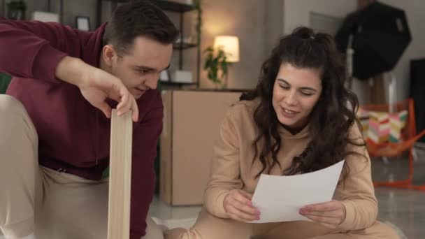 joven pareja moviéndose en nuevo apartamento llevar muebles de montaje - Metraje, vídeo