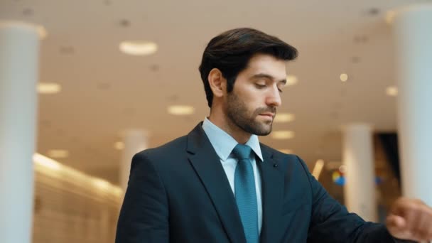 Caucasian smart business man looking at watch while waiting colleague. Executive manager wearing suit while standing at mall with blurred background. Investor wear blue suit checking time. Exultant. - Footage, Video