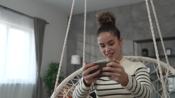 1人の若い女性が自宅で携帯電話のスマートフォンビデオゲームをプレイ - 映像、動画