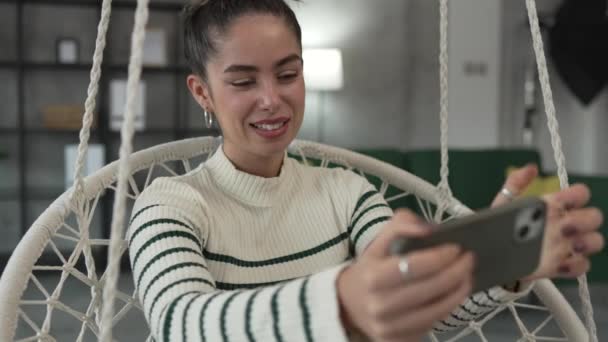 Een jonge vrouw spelen mobiele telefoon smartphone video game thuis - Video