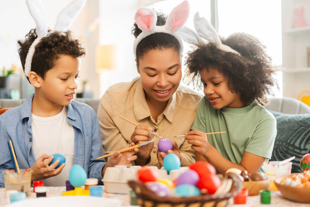 Carino sorridente famiglia latina: madre e bambini indossano orecchie da coniglio pittura uova di Pasqua a casa - Foto, immagini