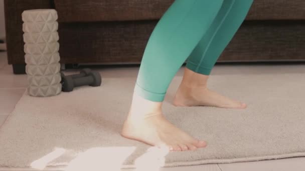 Sportliche Frauen trainieren zu Hause im Wohnzimmer Kniebeugen und Ausfallschritte. Athletische Mädchen im Training. Training und Durchführung von körperlichen Übungen mit einem Seil, Fitness-Gummiband. Sportkonzept - Filmmaterial, Video