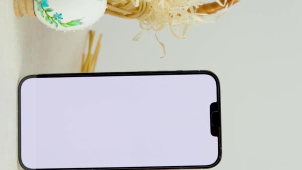 Easter holiday phone show thumb up empty space for advertising In basket eggs with embroidered pattern ribbon embroidery on eggshells wheat spikelets on table place for dough close-up basket - Footage, Video