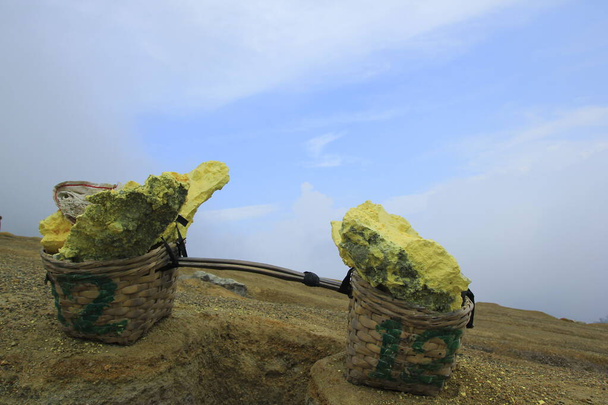 Серный камень помещается в корзину для транспортировки шахтерами в кратер Иджен, Восточная Ява, Индонезия - Фото, изображение