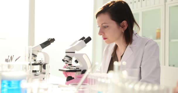 Laboratório de desenvolvimento médico da bela mulher cientista olhando sob microscópio e analisando amostras juntos. Medicina pesquisa biotecnológica em laboratório - Filmagem, Vídeo
