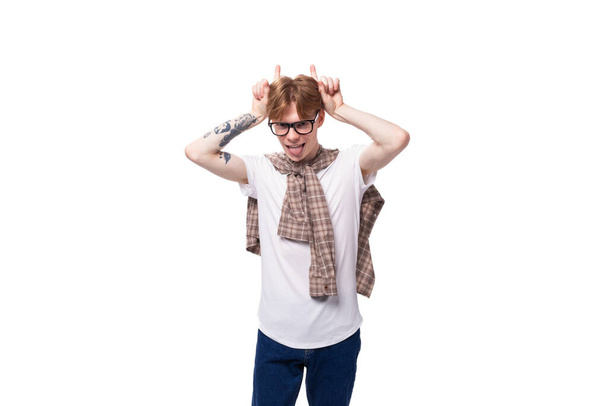 портрет стильного рыжего парня в очках и клетчатая рубашка на фоне студии. - Фото, изображение