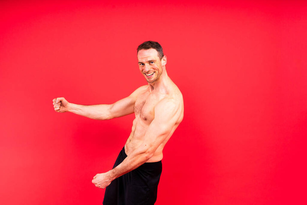 Образ м'язового чоловіка, який позує в студії, темно-білий червоний фон - Фото, зображення