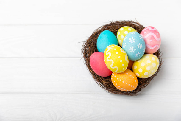 Ovos de Páscoa coloridos em um ninho e um buquê de tulipas em uma mesa de madeira texturizada. Conceito de celebração da Páscoa. Páscoa colorido artesanal decorado ovos de Páscoa. Lugar para SMS. Espaço de cópia - Foto, Imagem