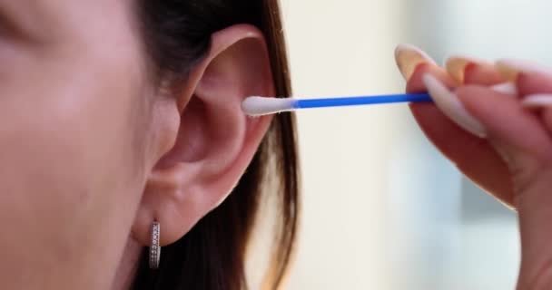 Giovane donna pulisce l'orecchio con tampone di cotone. Igiene delle orecchie e assistenza sanitaria - Filmati, video