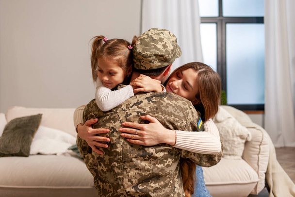 homem militar do exército ucraniano em uniforme de camuflagem voltou para casa e abraça sua família, soldado vai para a guerra e se despede de sua filha e esposa, o conceito de mobilização na Ucrânia - Foto, Imagem