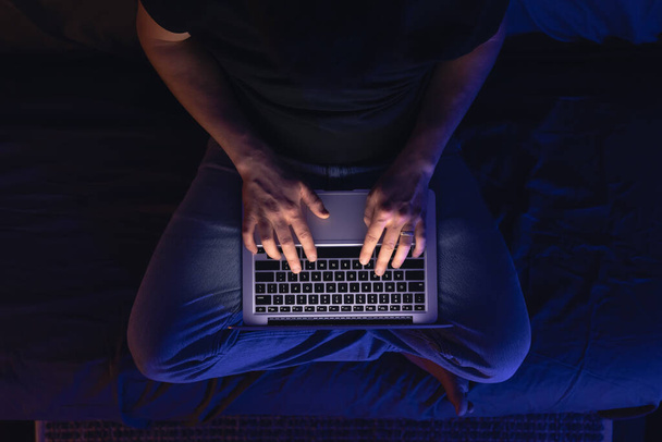 Крупним планом хакерська рука краде дані, людина спілкується на ноутбуці пізно ввечері. Безсоння та комп'ютерна залежність. - Фото, зображення