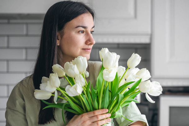 Mulher feliz desfrutar de buquê de tulipas brancas. Dona de casa desfrutando de um monte de flores e interior da cozinha. Lar doce. Sem alergias. - Foto, Imagem