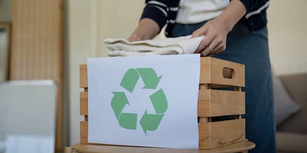 Frau packt Schachtel mit gebrauchter Kleidung zur Wiederverwendung. Wiederverwendung, Recycling von Material und Reduzierung von Abfall in Mode, Second-Hand-Bekleidung Idee. Kreislauf-Mode, Null-Abfall-Konzept. - Foto, Bild