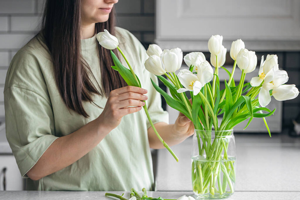 Boldog nő élvezi a tulipán csokrot. Háziasszony élvezi a sok virágot a konyha belsejében. Édes otthon. Allergiamentes. - Fotó, kép