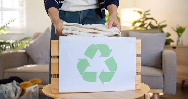 Une jeune femme sépare les vêtements inutilisés et les prépare au don ou au recyclage afin de réduire la pollution atmosphérique et de protéger l'environnement.. - Photo, image