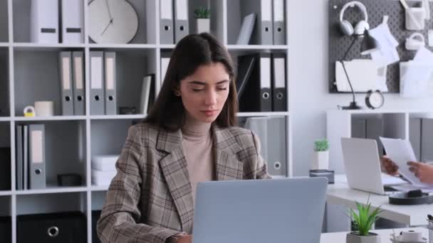 Thoughtful Caucasian businesswoman working with laptop sitting at desk in the office. Typing or texting, reading information, planning work. - Footage, Video