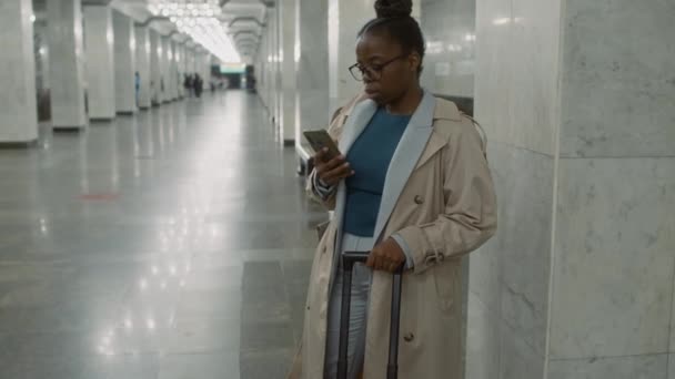 Imágenes laterales inclinadas del turista afroamericano con ruta de planificación de maletas mirando la pantalla del teléfono y luego corriendo para coger el tren de metro de tránsito - Imágenes, Vídeo