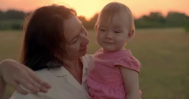 Madre feliz con su linda niña con tonos de atardecer en el parque - Imágenes, Vídeo