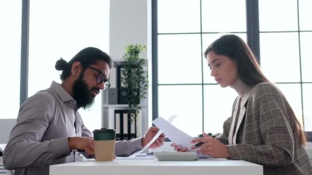 Concentrated coworkers, Indian man and Caucasian woman doing paperwork in modern office during meeting. Research, planning, analysis, brainstorming concept. - Footage, Video