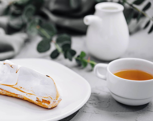 eclair com merengue e xícara de chá - Foto, Imagem