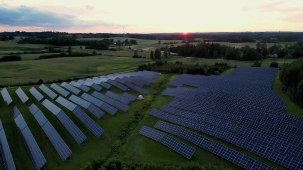 Drone filmato di una centrale solare al tramonto fattoria solare con pannelli fotovoltaici conversione di energia solare in energia elettrica per l'energia verde, Pannelli solari in Estonia sfondo tramonto in estate. - Filmati, video