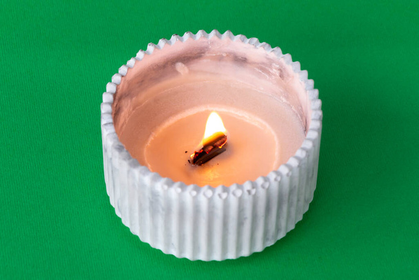 горящая свеча в штукатурке, крупным планом на цветном фоне - Фото, изображение