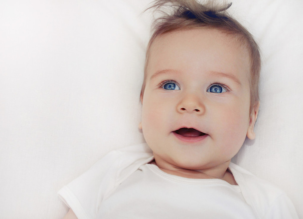 柔らかい白いピロに横たわってかわいい幸せな赤ちゃん男の子の肖像画 - 写真・画像