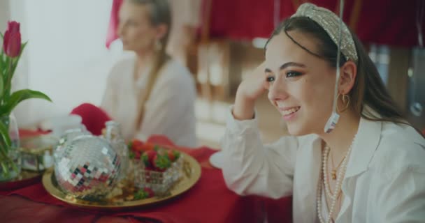 Szczęśliwa młoda kobieta rozmawia siedząc przy stole podczas uroczystości Galentines Day w domu - Materiał filmowy, wideo