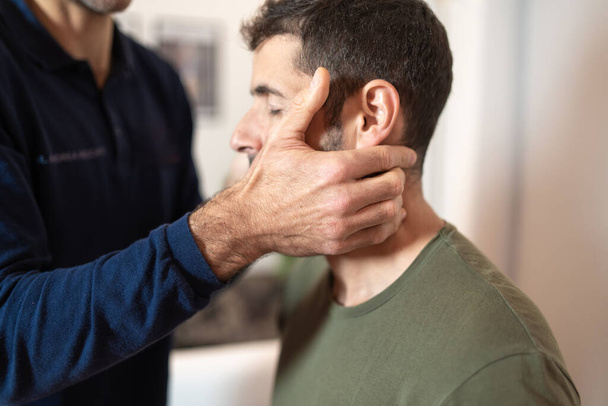 A physical therapist carefully performing a neck adjustment on a patient, using osteopathic manual techniques to alleviate cervical discomfort. - Foto, immagini
