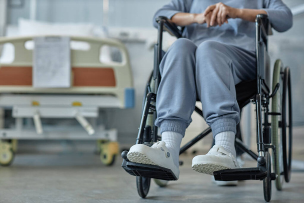 Primer plano del paciente mayor con discapacidad sentado en silla de ruedas durante la rehabilitación en la sala de hospitalización - Foto, Imagen