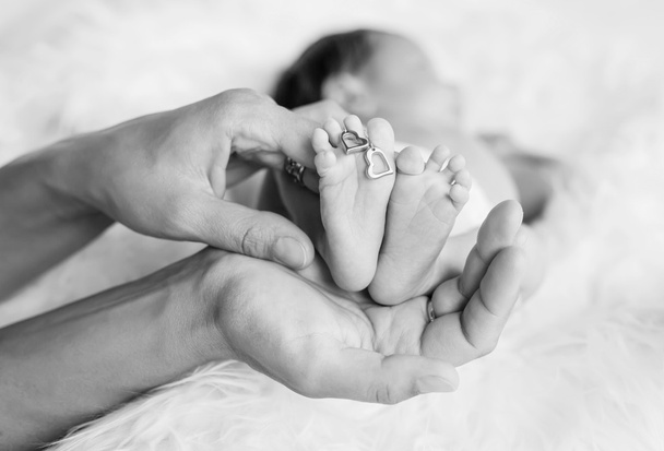 Vastasyntyneen lapsen jalka huolehtivissa käsissä
 - Valokuva, kuva