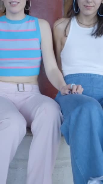 Три дівчини в барвистому одязі сидять і показують роликові ковзани на камеру - FullHD Вертикальне відео - Кадри, відео