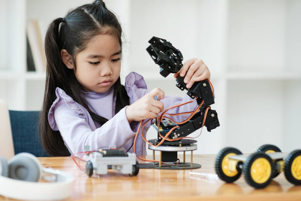 Ασιάτισσα που επικεντρώνεται στην κατασκευή ενός ρομπότ, που ενσωματώνει την εκπαίδευση STEM. - Φωτογραφία, εικόνα