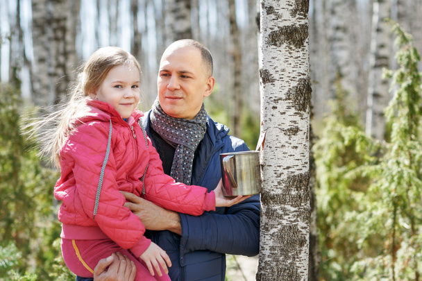 family to wood collecting birch sap in mug - Photo, Image