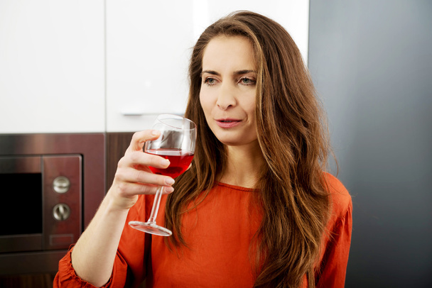 Woman with his wineglass in the kitchen. - Фото, изображение