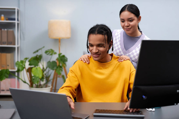 Προσωπογραφία δύο νέων ανδρών και γυναικών που αναθεωρούν τον κώδικα μαζί ενώ εργάζονται στο γραφείο ανάπτυξης της πληροφορικής και χρησιμοποιούν υπολογιστές - Φωτογραφία, εικόνα