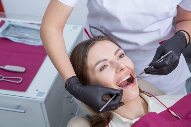 Stomatologia i pielęgnacja zębów. Dentyzm i zdrowie jamy ustnej. Kobieta ma badania zębów w klinice stomatologicznej. zbliżenie młody kaukaski dziewczyna twarz. - Zdjęcie, obraz