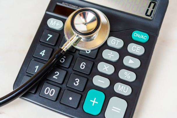 Estetoscópio e calculadora na tabela. Custos médicos, despesas de cuidados de saúde, encargo financeiro da doença - Foto, Imagem