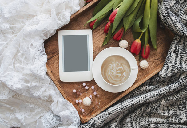 Composición romántica con taza de café, tulipanes rojos y lector electrónico con espacio para copiar en bandeja de madera. Plantilla para blog femenino redes sociales. - Foto, imagen