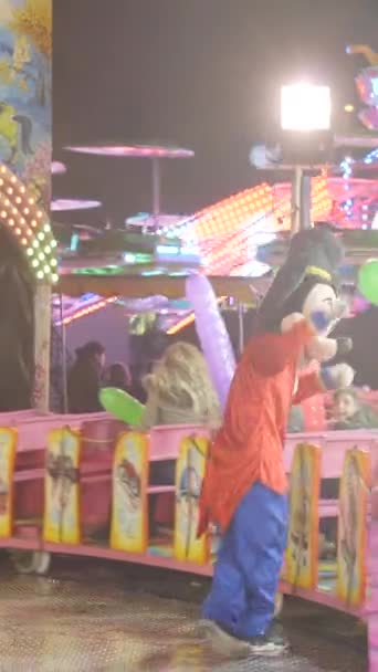 バレンシアの楽しいフェア - ミッキーマウスの衣装の男は,夜の"トレンチャック"アトラクションで電車に乗っている子供を楽しませます - FullHD垂直ビデオ - 映像、動画