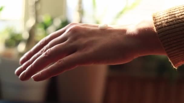 Κρέμα χεριών. Γυναικεία χέρια απλώστε αντιγηραντική κρέμα στο δέρμα, κοντινό πλάνο. Ενυδατική κρέμα χεριών. Φροντίδα δέρματος - Πλάνα, βίντεο
