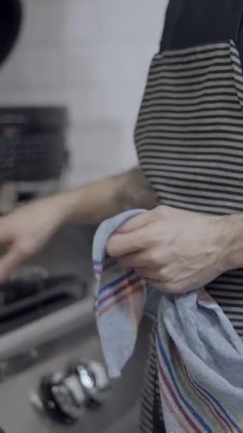 エプロンを着用したタトゥー付き男性シェフは,レストランのキッチンで動作します, 顔なし - FullHD垂直ビデオ - 映像、動画