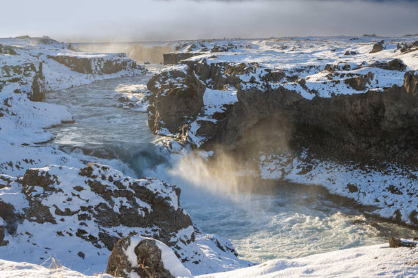 Parte della famosa cascata. Retroilluminazione del sole invernale. L'aria piena di vapore, spray e nebbia. Godafoss, Islanda del Nord. - Foto, immagini