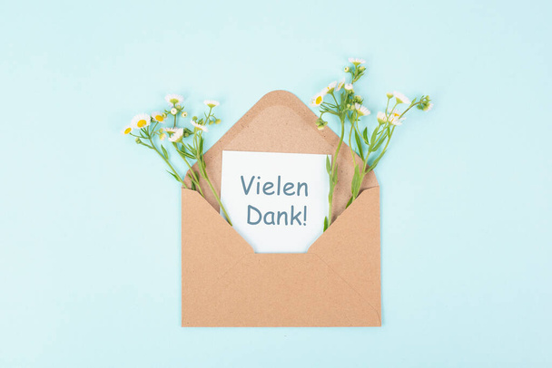 Thank you card, german language, envelope surrounded by spring flowers, being thankful, support, help and charity concept, positive attitude  - Photo, Image